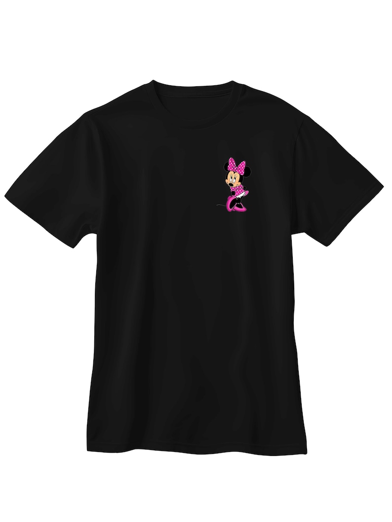 May include: Black t-shirt featuring a pink Minnie Mouse graphic. The graphic shows Minnie Mouse in a pink polka dot dress, bow, and shoes. The design is on the left chest area of the shirt. The t-shirt is made of a soft material.