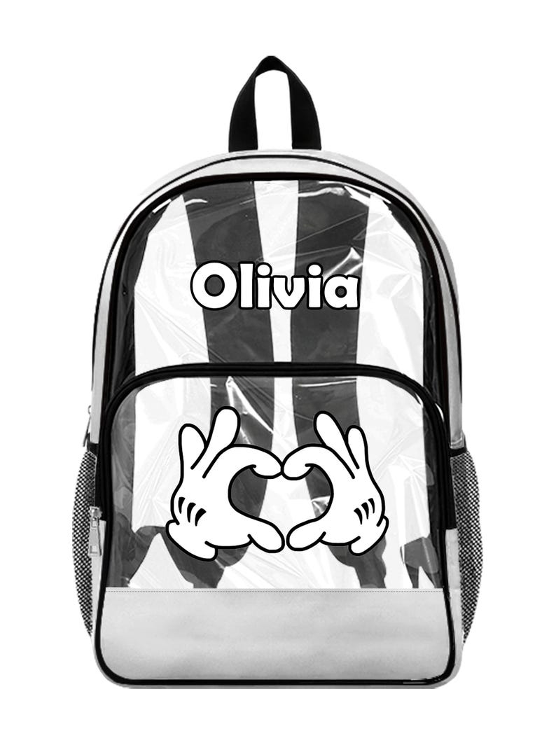 Peut inclure: Sac &agrave; dos transparent avec int&eacute;rieur &agrave; rayures noires et blanches. Comporte le nom "Olivia" en lettres blanches et un c&oelig;ur fait de mains de dessins anim&eacute;s blanches. Avec garniture noire et base blanche.