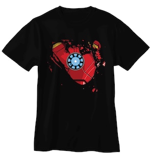 May include: Black t-shirt featuring a graphic design of Iron Man's arc reactor and chest armor. The design is red, gold, and blue, with a distressed, torn effect. The shirt is a short-sleeved crew neck.