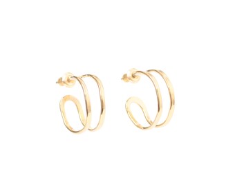 May include: A pair of gold hoop earrings with a double-layered design. The earrings are made of a smooth, shiny metal.