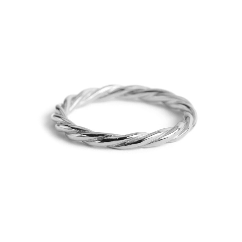 May include: A polished silver ring featuring a continuous twisted rope design. The band has a uniform thickness and a reflective metallic surface, creating a circular shape with a textured, spiraling pattern throughout the entire circumference.