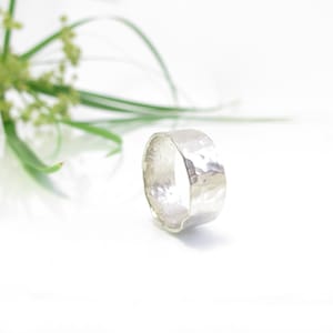 May include: A wide silver band ring with a hammered texture.