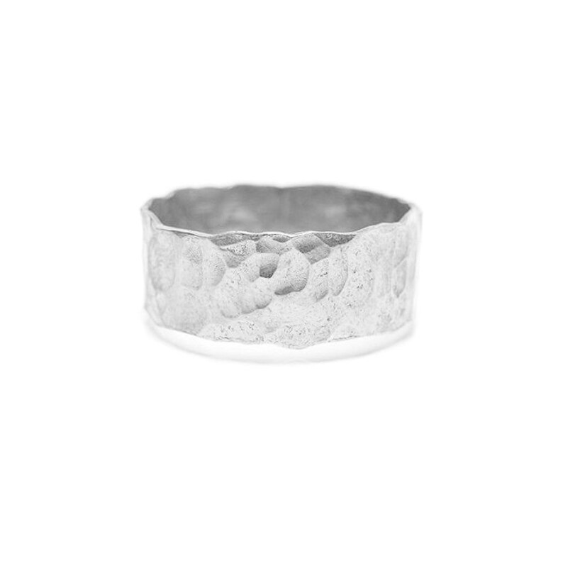 May include: A silver ring with a hammered texture. The ring is wide and has a rounded shape.