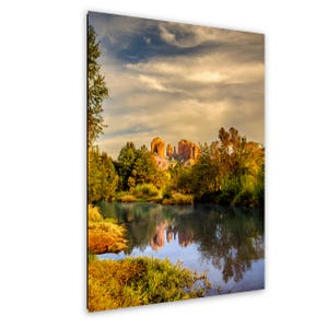 May include: A scenic landscape print featuring a tranquil lake reflecting the surrounding trees and rock formations. The sky is filled with clouds, and the overall color palette includes greens, blues, and warm golden hues.