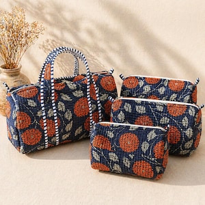 Può includere: Un set di borse e pochette trapuntate blu navy con un motivo floreale arancione e beige. La borsa più grande ha manici e un bordo a righe. Il set include una borsa da viaggio e tre pochette con cerniera.