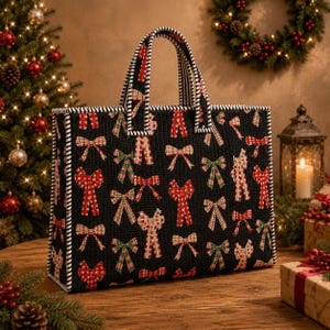 Könnte beinhalten: Schwarze Tragetasche mit einem sich wiederholenden Muster aus roten, grünen und cremefarbenen Schleifen. Die Tasche hat eine gesteppte Textur mit weiß-schwarzem Streifenbesatz und Griffen. Sie steht auf einer Holzoberfläche, mit einem Weihnachtsbaum und einem Kranz im Hintergrund.