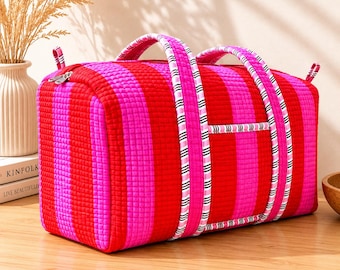 Pode incluir: Uma mala de viagem acolchoada com riscas verticais vermelhas e rosa. A mala tem alças resistentes e um fecho de correr. As alças são adornadas com riscas brancas e pretas. Um acessório de viagem elegante e prático.