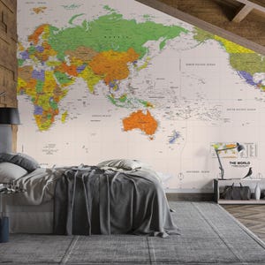 May include: A large-scale wall mural featuring a colourful political world map with labelled continents, countries, and oceans. The map displays text including 'THE WORLD' in the bottom right corner, with a light cream background and vibrant green, orange, yellow, and purple landmasses.