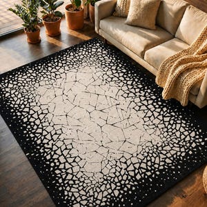 May include: A rectangular area rug with a black and off-white geometric pattern. The rug's design features a central off-white area with a cracked, mosaic-like appearance, fading into a black border. The rug is placed on a dark wooden floor.