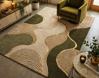 May include: A large rug with a beige, olive green, and gold colour scheme. The rug features an abstract design with flowing lines and textured patterns. The rug is placed in a living room setting with a green armchair and side table.