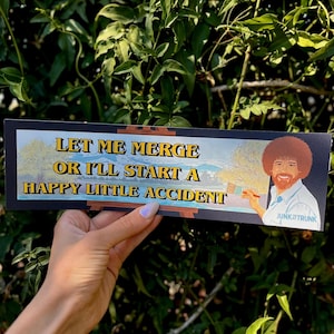 Puede incluir: Una pegatina rectangular para parachoques con la ilustración de un pintor con afro sosteniendo un pincel frente a un caballete. El texto dice: LET ME MERGE OR I'LL START A HAPPY LITTLE ACCIDENT. La esquina inferior derecha incluye JUNK TRUNK.