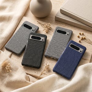 May include: Four rectangular smartphone cases with a textured fabric finish. Two cases are light gray, one is dark charcoal gray, and one is deep blue. Each case features a horizontal camera bar cutout at the top with visible lens openings.