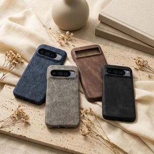 May include: Four rectangular smartphone cases with a textured fabric finish, featuring a horizontal camera cutout. The cases are available in navy blue, light gray, brown, and black, each designed to fit a specific mobile device model.