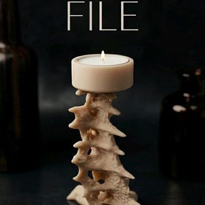 May include: A beige candle holder with a spine-like design, holding a lit tea light candle. The words "STL FILE" are displayed in white. The background is dark, with two dark brown bottles on either side.