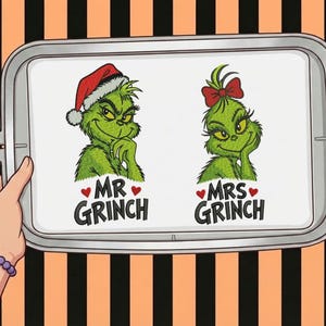 Peut inclure: Un tambour à broder contenant un tissu blanc avec deux personnages Grinch verts. Le personnage de gauche porte un bonnet de Père Noël rouge au-dessus du texte MR GRINCH avec des cœurs rouges. Celui de droite porte un nœud rouge au-dessus de MRS GRINCH.