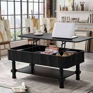 May include: A black coffee table with a lift-top mechanism, featuring a ribbed exterior design, four sturdy legs, and a lower storage shelf. The top surface holds a white mug and a silver laptop, while the interior compartment contains snacks.