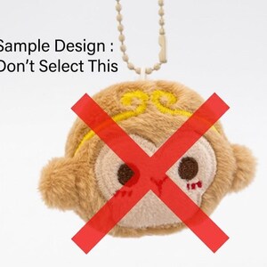 May include: A plush monkey keychain with a red 'X' over its face. The monkey is tan with a cream-colored face and yellow accents. The text "Sample Design: Don't Select This" is above the monkey.