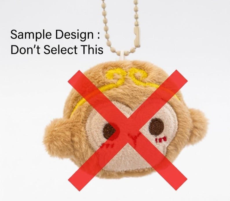 May include: A plush monkey keychain with a red 'X' over its face. The monkey is tan with a cream-colored face and yellow accents. The text "Sample Design: Don't Select This" is above the monkey.