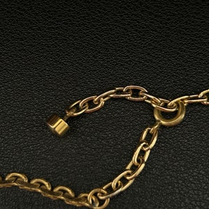 May include: A gold chain necklace with a lobster clasp closure. The chain is made of small, linked circles.