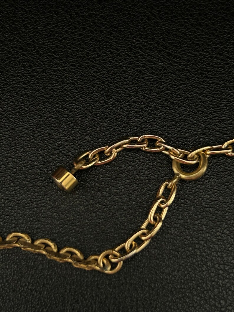 May include: A gold chain necklace with a lobster clasp closure. The chain is made of small, linked circles.