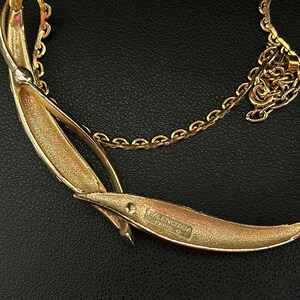 May include: A gold-toned necklace with a crescent-shaped pendant. The pendant has the text "BALENCIAGA PARIS" engraved on the back.