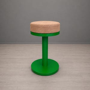 Könnte beinhalten: Ein moderner, minimalistischer Hocker mit einem runden, gepolsterten Sitz in Beige. Der Hocker hat eine leuchtend grüne Basis und eine zentrale Stütze. Die Basis ist eine kreisförmige Scheibe, und die Stütze ist ein zylindrischer Pfosten. Der Hocker ist etwa 46 cm hoch.