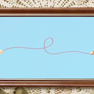 May include: A rectangular wooden frame with a dark brown finish containing a light blue background. A single thin red line stretches horizontally across the center, forming a small loop in the middle, held at each end by a finger.
