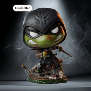 Puede incluir: Figura de una Tortuga Ninja en posición de combate, con casco y armadura negros. La figura de piel verde tiene una expresión enfadada y sostiene un arma. La base es un diorama detallado con una etiqueta de "Bestseller".