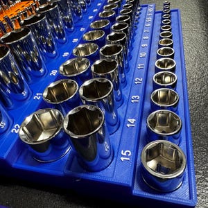 May include: A collection of chrome sockets displayed in a blue organiser. The sockets vary in size, with measurements from 5 to 22 visible. The sockets are arranged in rows, reflecting light.