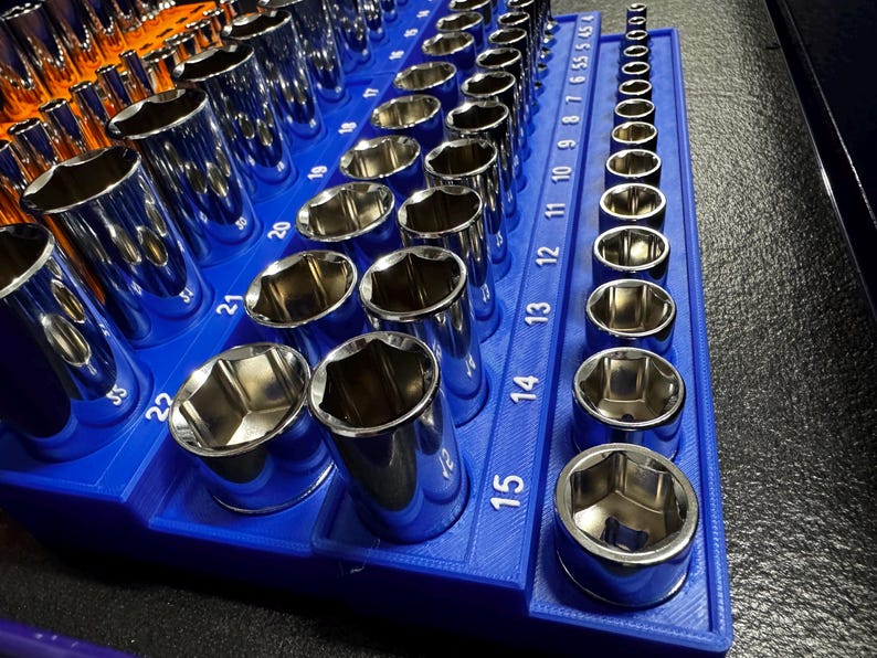 May include: A collection of chrome sockets displayed in a blue organiser. The sockets vary in size, with measurements from 5 to 22 visible. The sockets are arranged in rows, reflecting light.