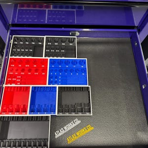 May include: A purple tool chest drawer with organized tool holders in red, blue, and black. The holders contain various sized sockets and bits. The text "ATLAS WORKS CO." is visible on a sticker.