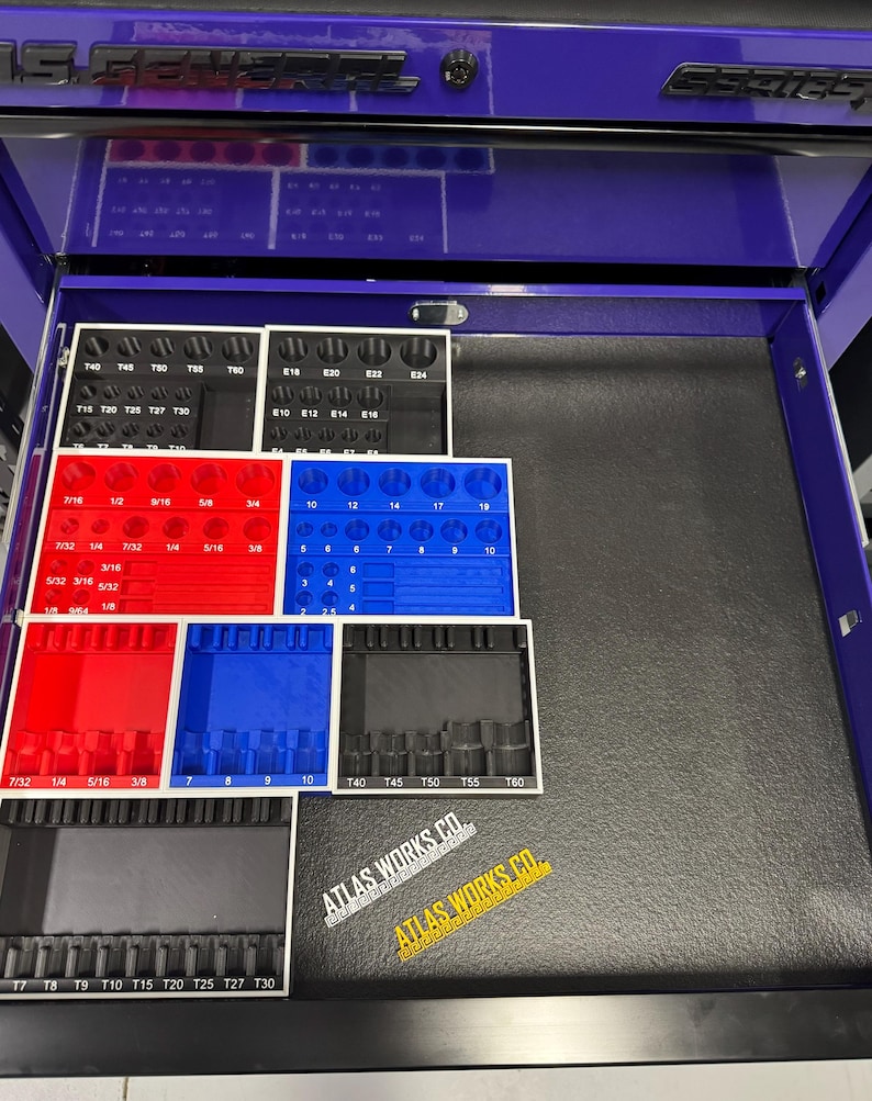 May include: A purple tool chest drawer with organized tool holders in red, blue, and black. The holders contain various sized sockets and bits. The text "ATLAS WORKS CO." is visible on a sticker.