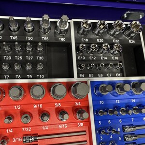 May include: A set of various metal sockets and bits, organized in a blue and red tray. The set includes different sizes and types of sockets, with labels such as T40, T45, T50, and E18, E20, E22.