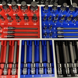 May include: A set of mechanic's tools, including sockets and bits, organized in red, blue, and white trays. The tools are labeled with sizes in inches and fractions of an inch, such as 1/4, 5/16, and 3/8.