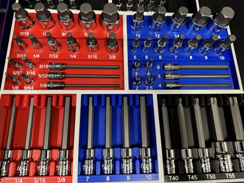 May include: A set of mechanic's tools, including sockets and bits, organized in red, blue, and white trays. The tools are labeled with sizes in inches and fractions of an inch, such as 1/4, 5/16, and 3/8.