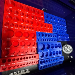 May include: Red and blue socket organizers with various sized holes, labeled with fractional inch measurements. The organizers are arranged in a toolbox, with the "ATLAS WORKS CO." logo visible.