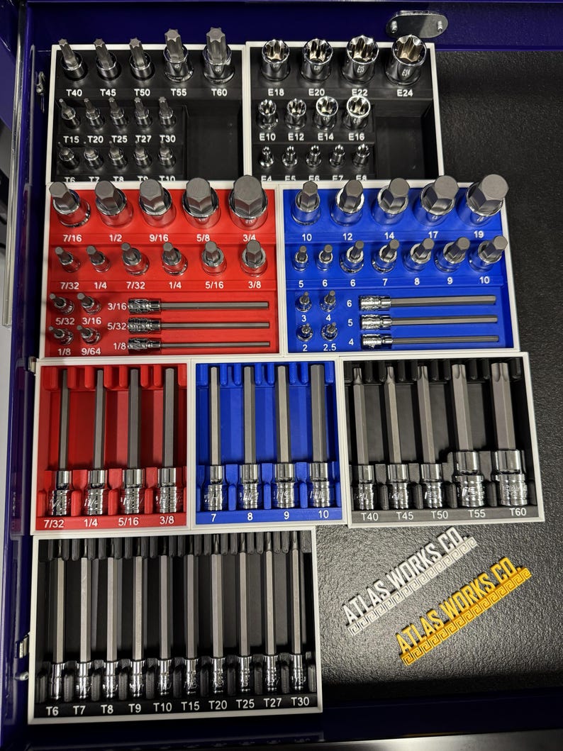 May include: A collection of various metal socket bits and hex keys, neatly organized in a blue toolbox. The set includes a variety of sizes, labeled with measurements in inches and fractions. The brand name "ATLAS WORKS CO." is visible.