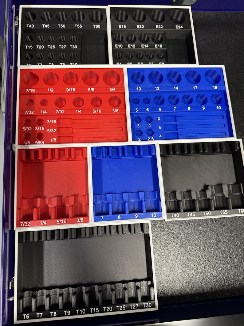 May include: A set of black, red, and blue socket organizers with various sizes and labels. The organizers are arranged in a tray, with sizes including 1/8, 1/4, 5/16, and 3/8 inches. The labels include T40, T45, T50, T55, and T60.