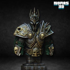 May include: A detailed bust of fantasy armour, featuring a helmet with a crown and intricate shoulder pauldrons. The armour is primarily metallic with gold and bronze accents, adorned with skull motifs. The bust is mounted on a stone base, with the text "NORAS 3D" in the upper right corner.