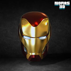 Può includere: Un casco di Iron Man dorato e rosso con fessure blu per gli occhi. Il casco ha una finitura lucida ed è esposto su uno sfondo scuro. Il testo "NORAS 3D" si trova nell'angolo in alto a destra.