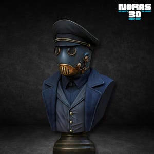 Può includere: Un busto di una figura che indossa un cappello e un cappotto blu scuro in stile militare, con una maschera antigas. La maschera antigas è blu scuro con dettagli dorati. Il busto è montato su un piedistallo scuro. Il testo "NORAS 3D" è nell'angolo in alto a destra.