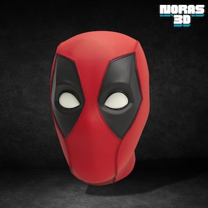 Puede incluir: Una máscara roja de Deadpool con contornos negros para los ojos y la boca y lentes blancos para los ojos. La máscara es una réplica del casco del personaje. El texto "NORAS 3D" está en la esquina superior derecha.