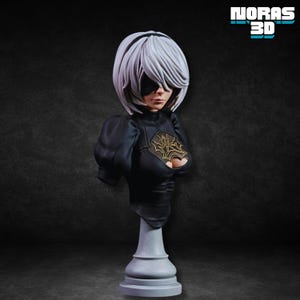 Pode incluir: Busto detalhado de uma personagem com cabelo curto branco, venda preta e roupa preta com detalhes dourados. O busto é montado em um pedestal cinza. O texto "NORAS 3D" está no canto superior direito.