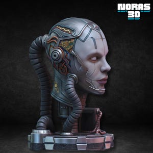 Pode incluir: Escultura futurista de uma cabeça humana com melhorias cibernéticas. A cabeça é predominantemente prateada com detalhes em cobre e ouro, apresentando um design detalhado com tubos e componentes mecânicos. A escultura está montada numa base metálica, com o texto "NORAS 3D".