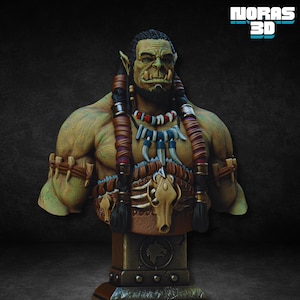 Könnte beinhalten: Detaillierte Büste eines Orcs mit grüner Haut, Stoßzähnen und geflochtenem Haar. Der Orc trägt Stammes-Schmuck, darunter eine Halskette mit Zähnen und einen Knochenschädel-Anhänger. Die Büste ist auf einem Steinsockel mit einem Wolfsemblem montiert. Der Text "MORAS 3D" ist sichtbar.