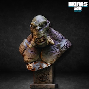Puede incluir: Busto detallado de un orco de piel verde con una expresión amenazante, colmillos prominentes y un aspecto desgastado. La escultura está montada sobre un pedestal de piedra con un emblema del árbol de la vida, mostrando detalles y texturas intrincados.