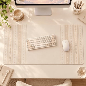 May include: A rectangular desk mat in a light beige color featuring a repeating pattern of vertical stripes and small geometric shapes. The mat is positioned on a desk surface with a white mechanical keyboard and a white computer mouse placed on top.
