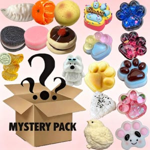 Puede incluir: Una colección de objetos decorativos coloridos, incluyendo figuras con forma de alimentos y animales. El surtido presenta una variedad de diseños, como una empanadilla, una rodaja de naranja, una galleta, una huella de pata y un oso. También hay una caja de cartón con el texto "MYSTERY PACK".