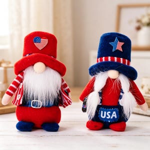Puede incluir: Dos figuras de gnomos patrióticos. Un gnomo lleva un sombrero rojo con una bandera estadounidense en forma de corazón, una chaqueta a rayas rojas y blancas y pantalones rojos. El otro gnomo tiene un sombrero azul con una estrella, un peto azul con "USA" y pantalones rojos.