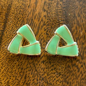 May include: A pair of green and gold triangle shaped earrings. The earrings are made of metal and have a smooth, glossy finish.